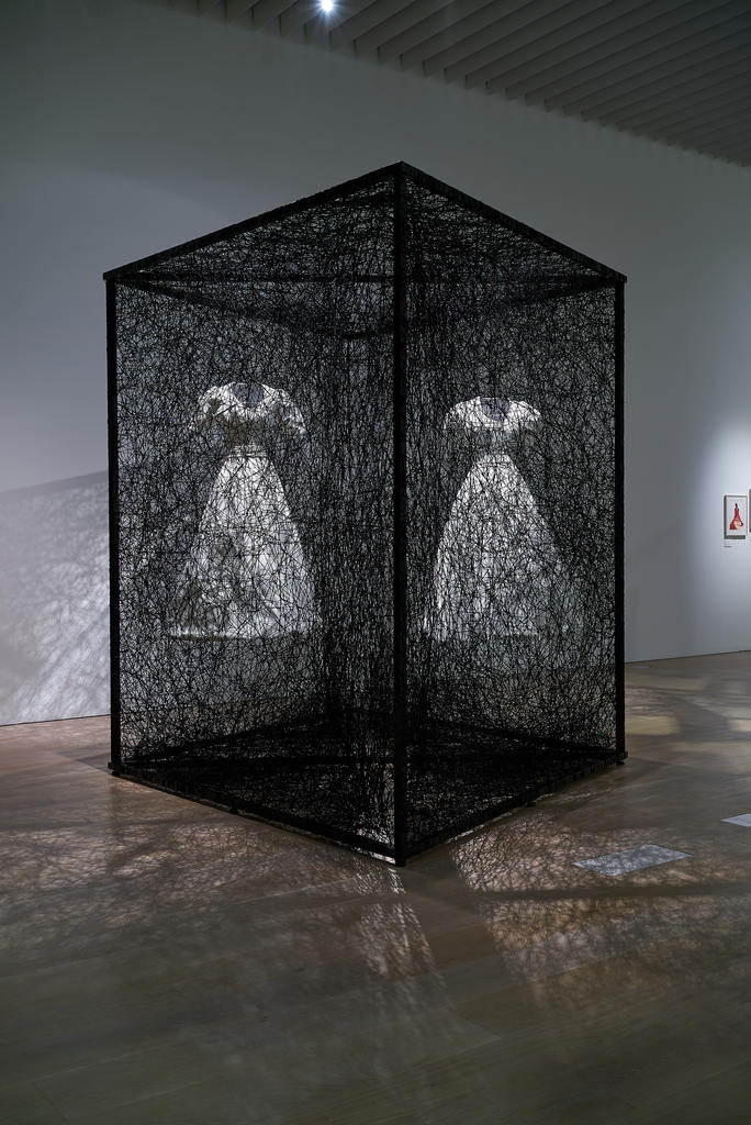 Chiharu Shiota (née en 1972), Reflection of Space and Time (« Reflet de l’espace et du temps »), 2018. Robes blanches, miroir, cadre métallique, fil noir Alcantara, 280 x 300 x 400 cm. Vue de l’installation : Nine Journeys through Time, Palazzo Reale Milano, 2018. Collection Alcantara S.p.A.